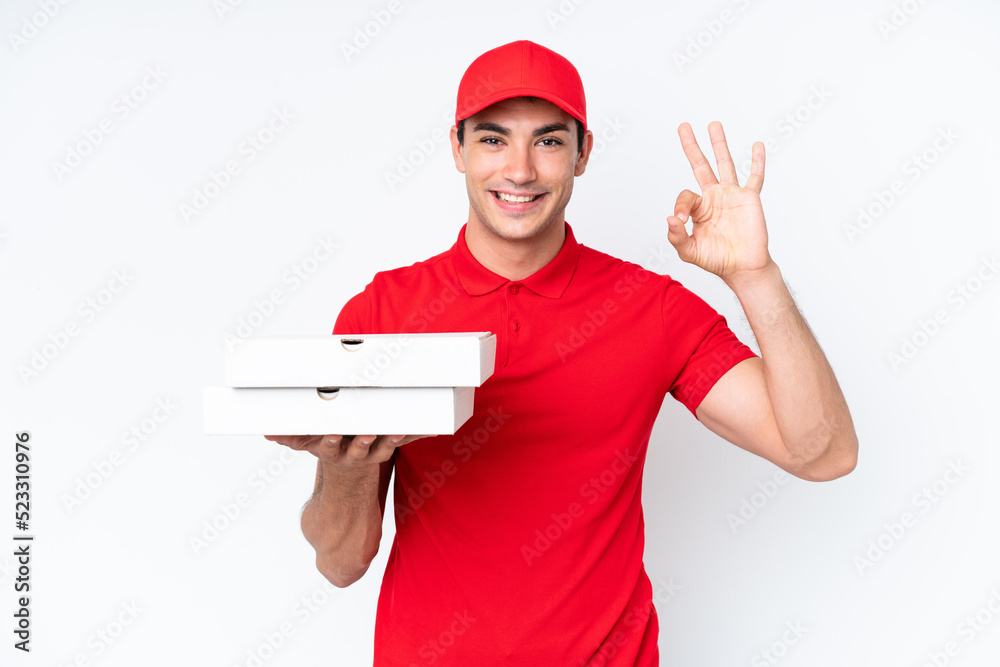 Pizza delivery caucasian man with work uniform picking up pizza boxes isolated on white background showing ok sign with fingers Pizza delivery caucasian man with work uniform picking up pizza boxes isolated on white background showing ok sign with fingers