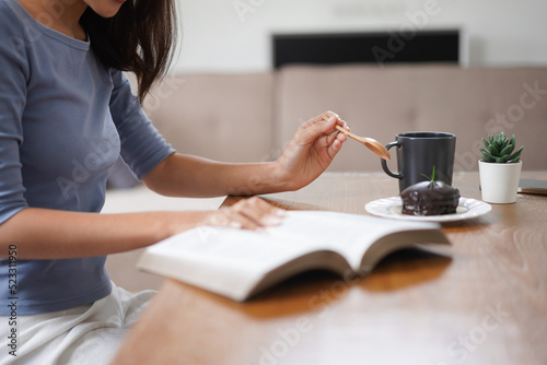 Work from home concept, Business women eats dessert and reads book to relax after working at home