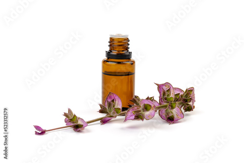 A bottle of essential oil with fresh blooming clary sage twigs on white background.