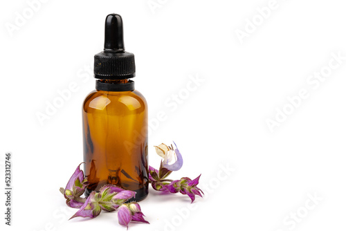 A bottle of essential oil with fresh blooming clary sage twigs on white background.