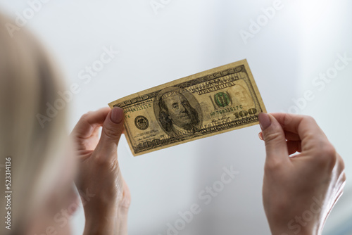 Checking counterfeit money light. 100 dollars against the window in his hand. Check for watermark on new hundred dollar bill. translucence of the American currency. photo