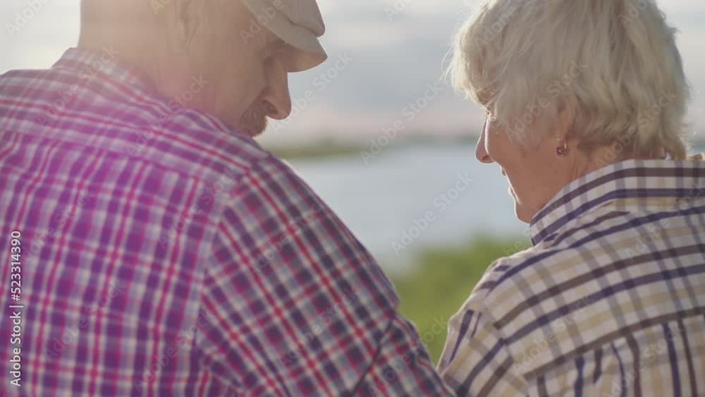 Happy old couple together embracing sitting on lake beach in sunshine outdoors. Candid affectionate feelings, live joyful human emotions, real harmony love, tenderness and care of two retired lovers Happy old couple together embracing sitting on lake beach in sunshine outdoors. Candid affectionate feelings, live joyful human emotions, real harmony love, tenderness and care of two retired lovers