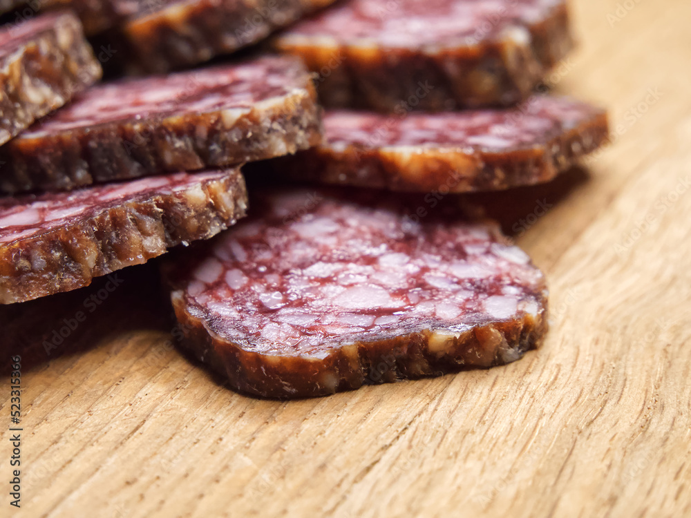 Closeup shot of sliced salami on the table. Pieces of delicious smoked sausage on a wooden cutting board, closeup shot. Closeup shot of sliced salami on the table. Pieces of delicious smoked sausage on a wooden cutting board, closeup shot.