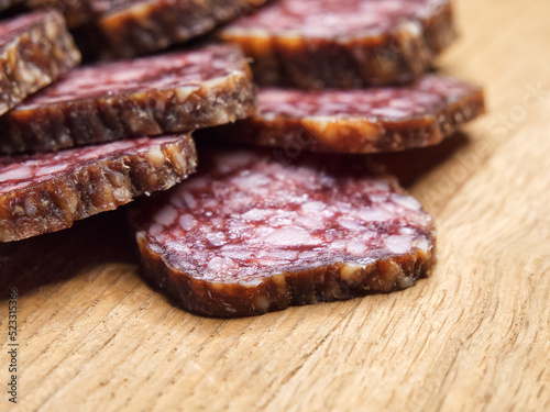 Closeup shot of sliced salami on the table. Pieces of delicious smoked sausage on a wooden cutting board, closeup shot.