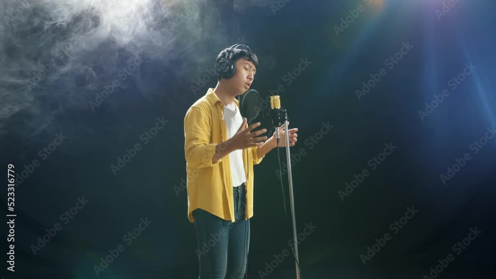 Young Asian Boy With Headphone Singing Into A Condenser Microphone On The White Smoke Black Background
Young Asian Boy With Headphone Singing Into A Condenser Microphone On The White Smoke Black Background