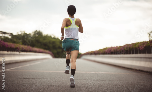Fitness woman runner running on city bridge road