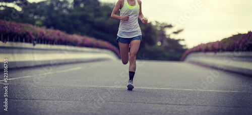Fitness woman runner running on city bridge road