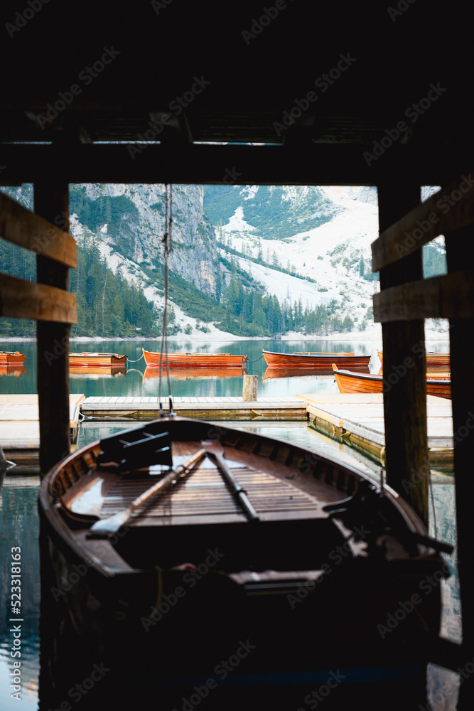 (Selective focus) Stunning view of some wooden boats floating on the Lake Braies (Lago di Braies) with defocused mountains in the distance. Lago di Braies is an alpine lake in the Dolomites, Italy