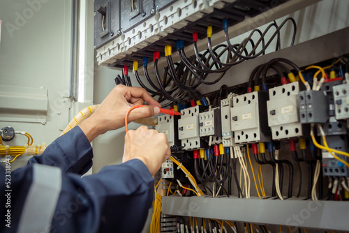 Electrical engineer using measuring equipment to checking electric current voltage at circuit breaker and cable wiring system , Electrical service concept .