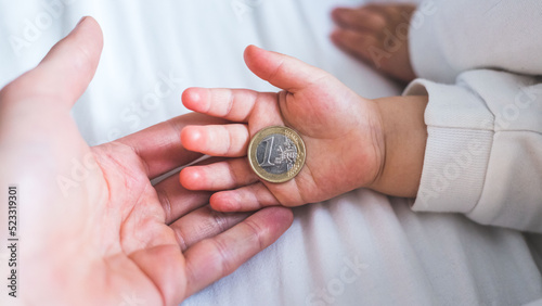 Inflation and financial security concept: Close up of newborn baby holding a euro coin