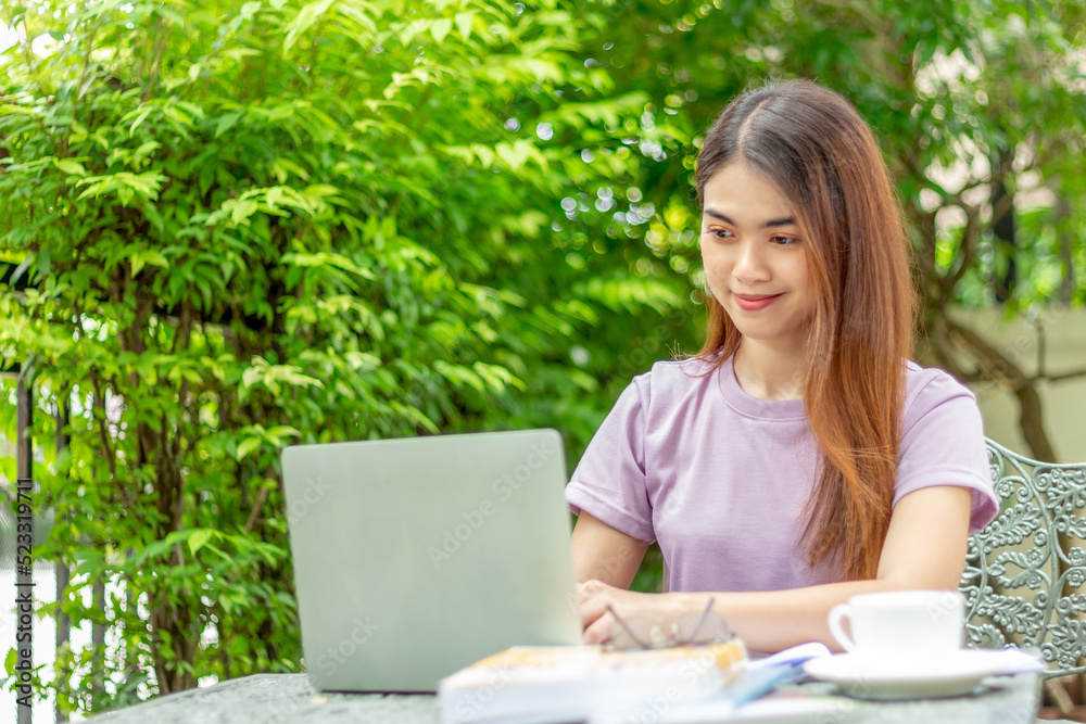 beauty woman doing freelance work in garden. Asian woman using laptop at home back yard with tree background copy space. beauty woman doing freelance work in garden. Asian woman using laptop at home back yard with tree background copy space.