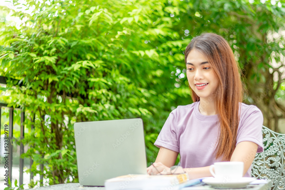 beauty woman doing freelance work in garden. Asian woman using laptop at home back yard with tree background copy space. beauty woman doing freelance work in garden. Asian woman using laptop at home back yard with tree background copy space.