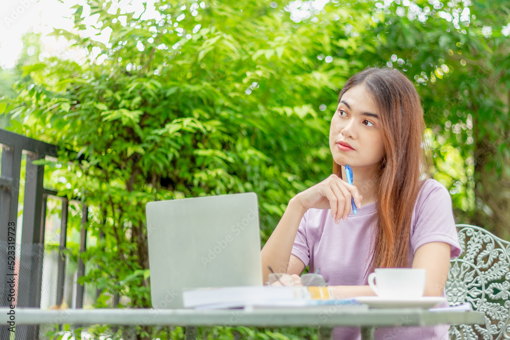 beauty woman doing freelance work in garden. Asian woman using laptop at home back yard with tree background copy space.
