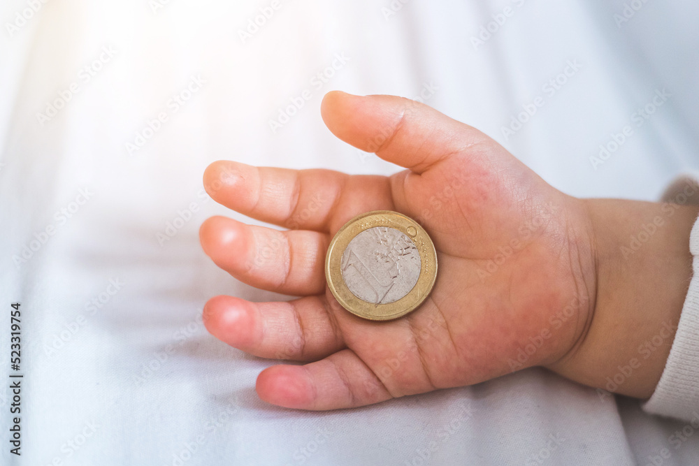 Inflation and financial security concept: Close up of newborn baby holding a euro coin