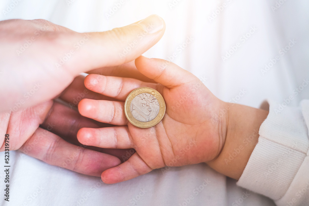 Inflation and financial security concept: Close up of newborn baby holding a euro coin Inflation and financial security concept: Close up of newborn baby holding a euro coin
