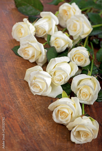 bouquet of white rose with green leaves on a wooden