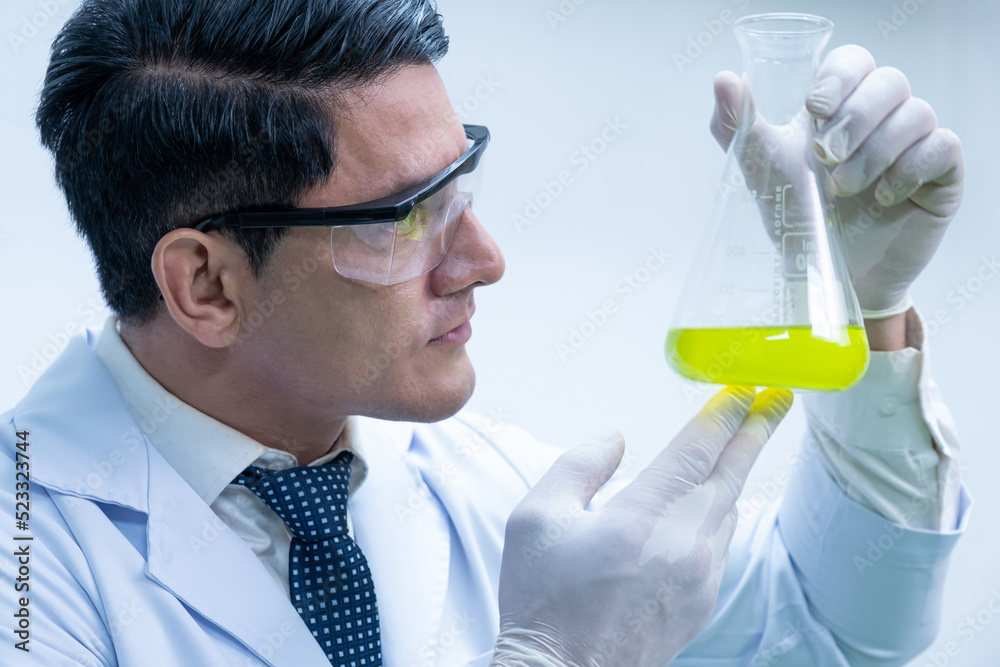Selective focus at eye of scientist, test tube while scientist study and examine with chemical or essential oil for medicine inside test laboratory. Chemical engineer work process. Selective focus at eye of scientist, test tube while scientist study and examine with chemical or essential oil for medicine inside test laboratory. Chemical engineer work process.