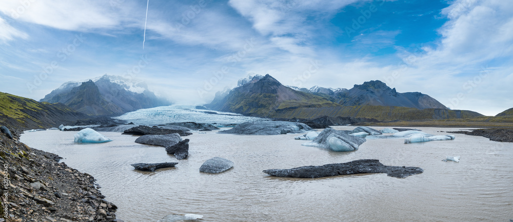 Obraz premium Glacier tongue slides from the Vatnajokull icecap or Vatna Glacier near subglacial Oaefajokull volcano, Iceland. Glacial lagoon with ice blocks and surrounding mountains.