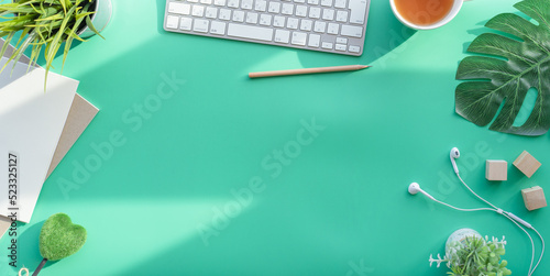 Flat lay of top view desk work table with Coffee computer notebook and pencil work space in minimal green color spring tone concept includes copyspace for add text or graphic