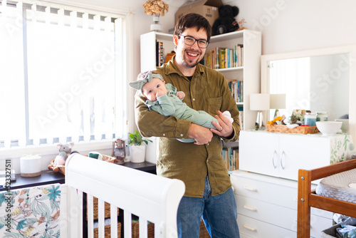 Happy young Aussie dad holding three month old baby daughter in home