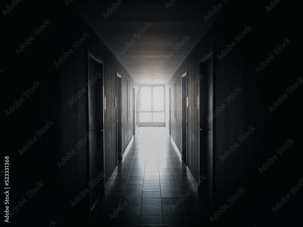 The light at the window at end of the way on dark mysterious corridor in building. Door room perspective in lonely quiet building with walkway, black and white style. hope, brave and fear concept.