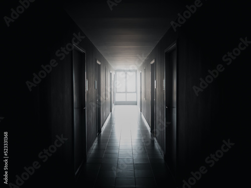 The light at the window at end of the way on dark mysterious corridor in building. Door room perspective in lonely quiet building with walkway, black and white style. hope, brave and fear concept.