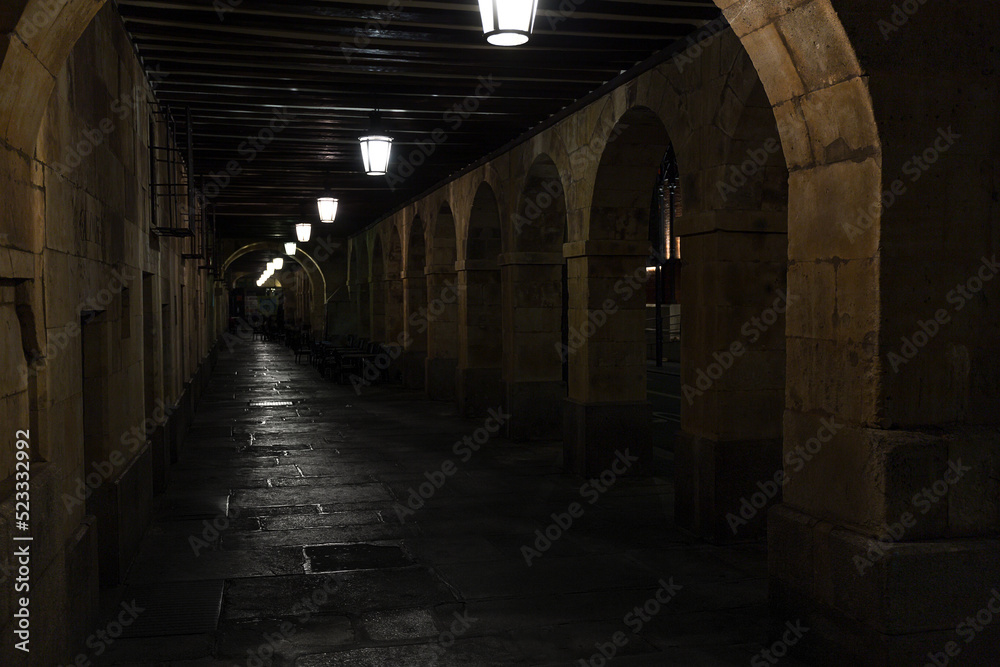 Stone arcades and iron lampposts hanging in the arcades of San Antonio outside the Plaza Mayor in Salamanca