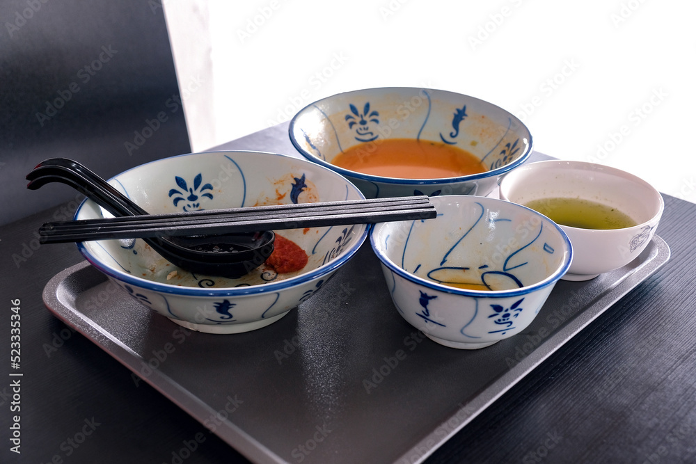Fotografia do Stock Tray of used crockery on table. Diners at coffee