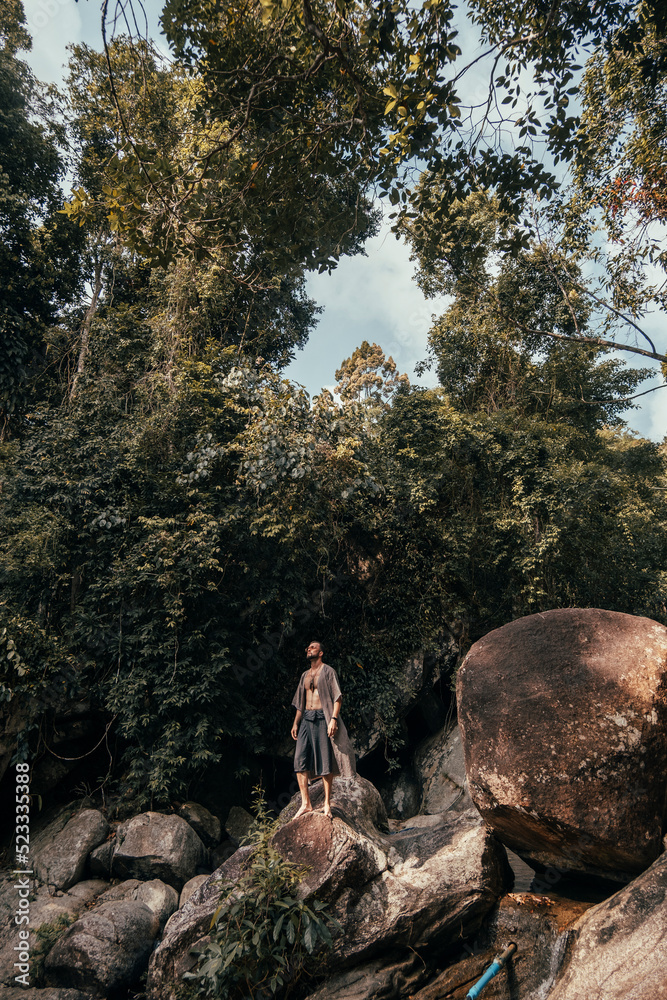 handsome bearded man posing on a mountain in the jungle, tourist traveler