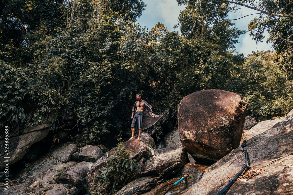 handsome bearded man posing on a mountain in the jungle, tourist traveler handsome bearded man posing on a mountain in the jungle, tourist traveler