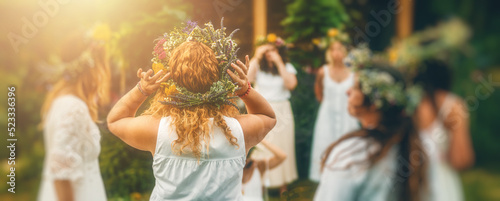 Women in flower wreath on sunny meadow, Floral crown, symbol of summer solstice.