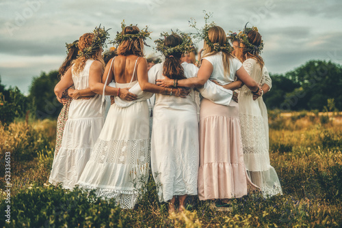 Women in flower wreath on sunny meadow, Floral crown, symbol of summer solstice. photo