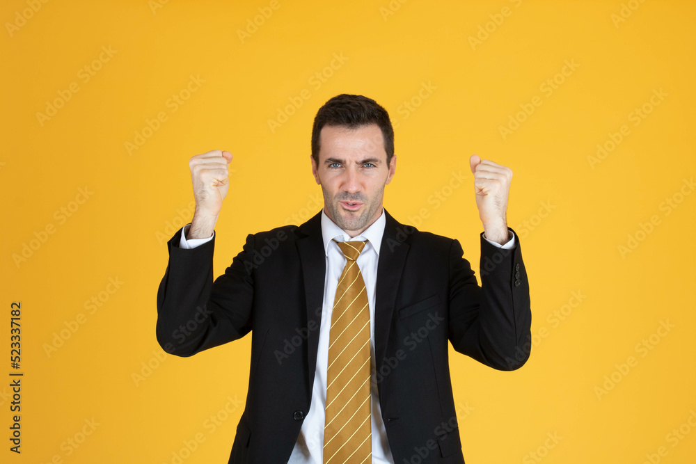 Portrait of a confident businessman is doing winner gesture on yellow background. Portrait of a confident businessman is doing winner gesture on yellow background.