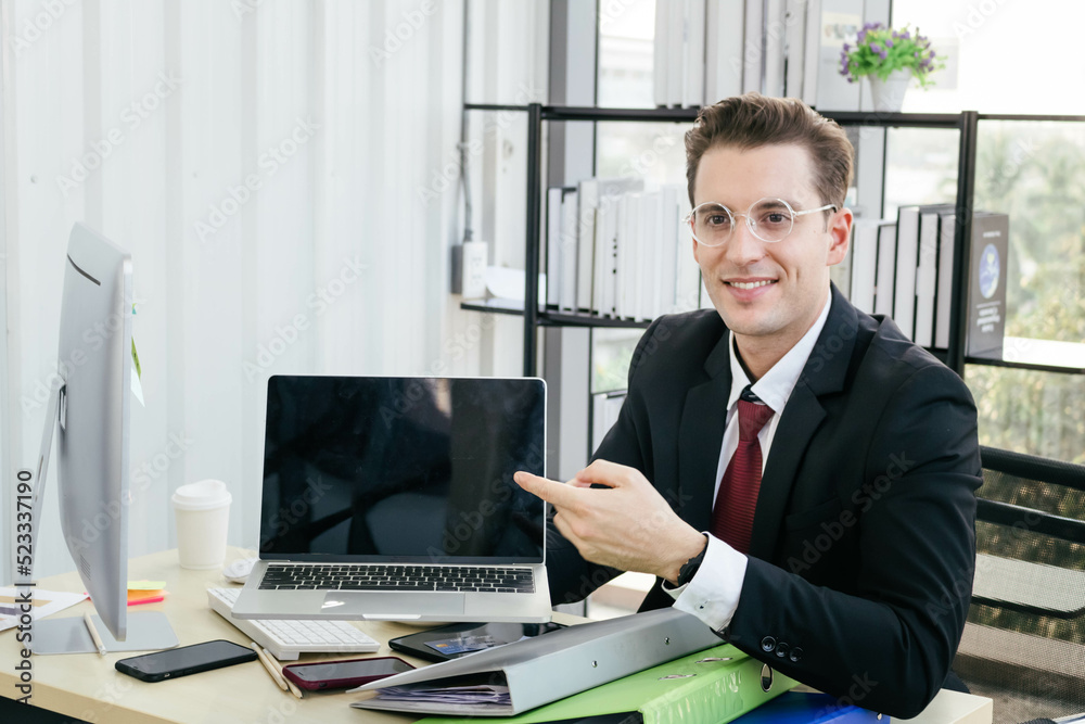 A young caucasian businessman presents his work on a laptop. Succesful work concept. A young caucasian businessman presents his work on a laptop. Succesful work concept.