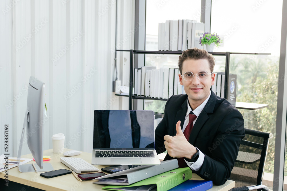 A young caucasian businessman presents his work on a laptop. Succesful work concept. A young caucasian businessman presents his work on a laptop. Succesful work concept.