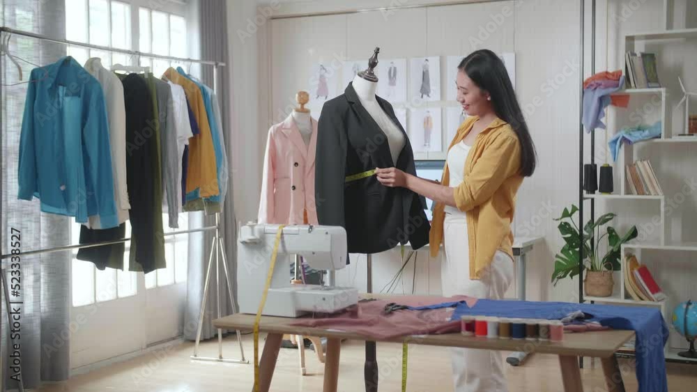 Smiling Asian Female Designer With Sewing Machine Measuring Business Jacket On A Mannequin While Designing Clothes In The Studio
Smiling Asian Female Designer With Sewing Machine Measuring Business Jacket On A Mannequin While Designing Clothes In The Studio