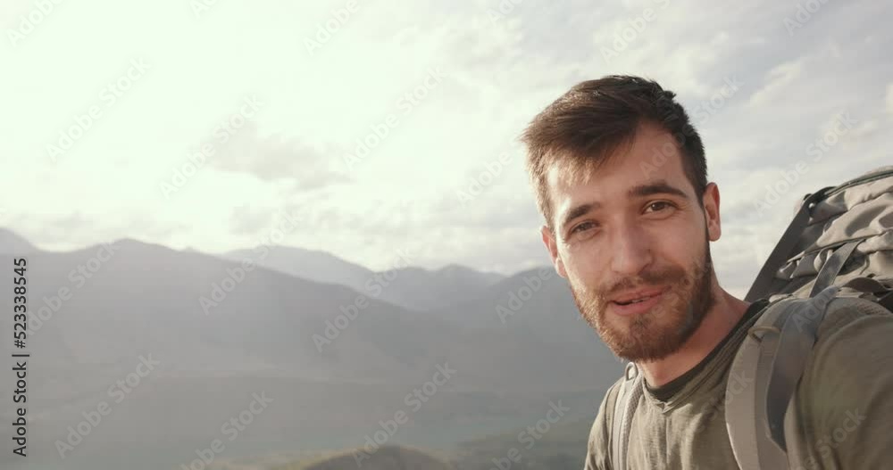 a young happy millennial spends a video chat with his family in the picturesque mountains. the blogger shares his impressions of the trip in a blog