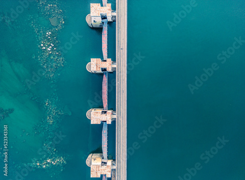 Top view of the dam, drainage of water through locks, industrial concept banner in blue. Visible river bed with huge stones © Daniel