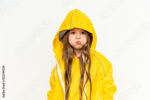 A child wearing a raincoat hood puffed out her cheeks on a white isolated background.