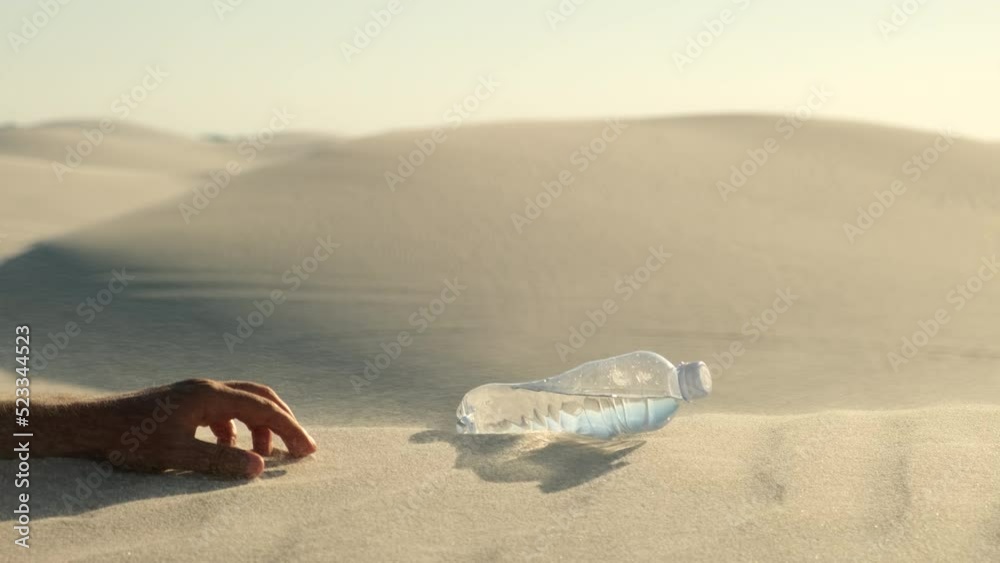 bottle with water on the desert. a plastic water bottle lies on the hot sand in the desert under the hot sun, alone in the middle of the desert sand. Hand takes a plastic water bottle in the desert. bottle with water on the desert. a plastic water bottle lies on the hot sand in the desert under the hot sun, alone in the middle of the desert sand. Hand takes a plastic water bottle in the desert.
