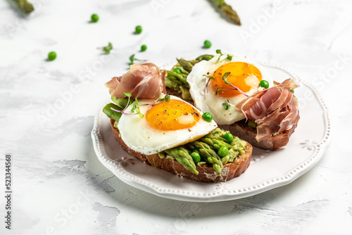 Grilled Toast witch Asparagus, fried egg, bacon jamon, ham, prosciutto on white background. Long banner format. top view