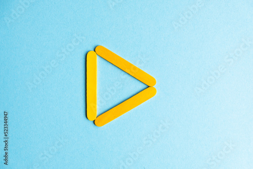 The play sign is yellow on a blue background. Inverted treulnik on a blue background. Geometric stick figure