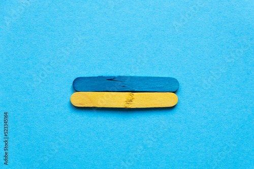 Flag of ukraine from wooden sticks on a blue background. War in Ukraine. The wooden sticks are broken. Symbol of war and suffering