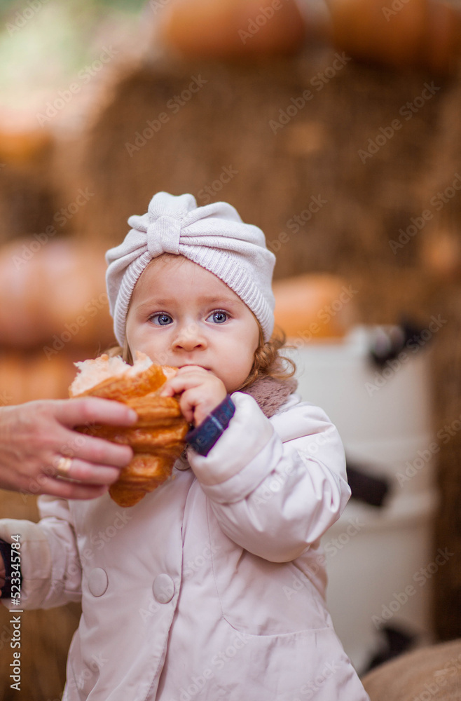 Little girl in beige coat eating croissant Childhood concept. Little girl in beige coat eating croissant Childhood concept.