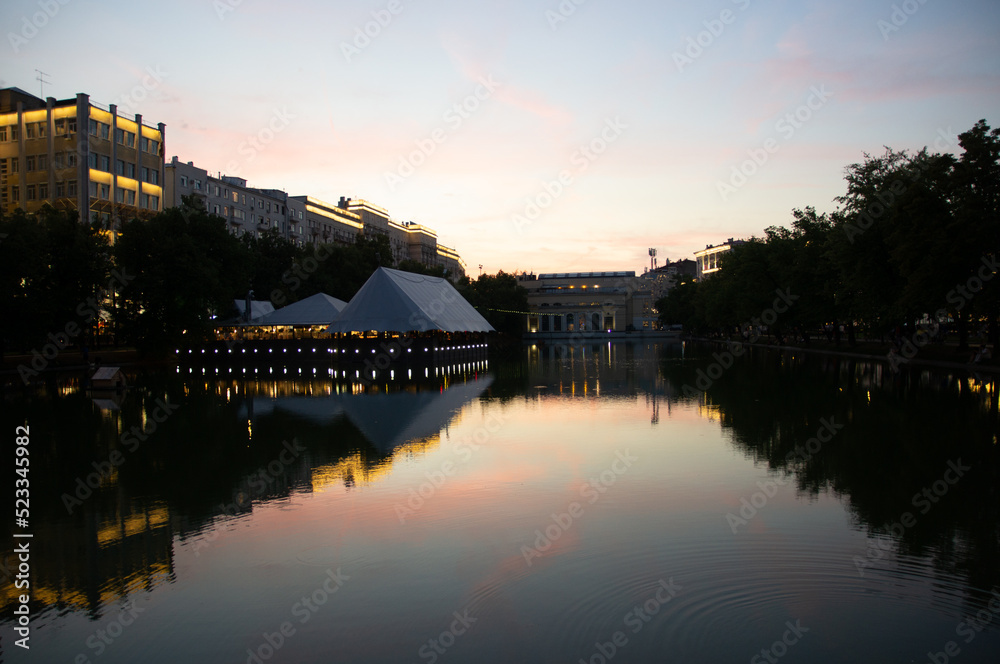 evening landscape on Chistoprudny Boulevard - Chistye Prudy, Moscow, Russia. Evening view of the city pond with ducks, a duck house and a cafe on the embankment