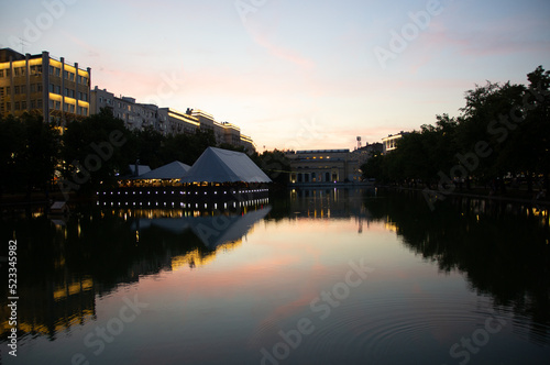 evening landscape on Chistoprudny Boulevard - Chistye Prudy, Moscow, Russia. Evening view of the city pond with ducks, a duck house and a cafe on the embankment