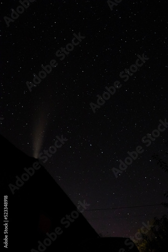 Starry sky with milky way above silhouette of chimney old house in village