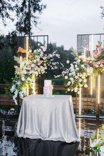 Beautiful wedding cake covered in chocolate velour with gradient and fresh flowers. Beautiful pink hydrangea. Outdoor registration area with a backdrop of a lake and green trees. 