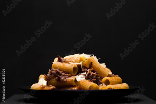 Pasta with stew on black background.