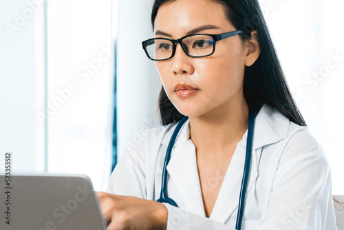 Asian woman doctor working online in medical office